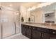 Bright bathroom featuring a double vanity with granite countertops and a glass enclosed shower at 11933 Norfolk Ct, Commerce City, CO 80022