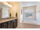 Bathroom featuring a soaking tub, granite countertop vanity, and window for natural light at 11933 Norfolk Ct, Commerce City, CO 80022