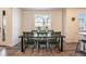 Bright dining room with green chairs surrounding a dark wood table, with a large window view at 11933 Norfolk Ct, Commerce City, CO 80022