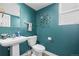 Stylish powder room with teal walls and decorative peacock wall decor at 8815 W Quarto Cir, Littleton, CO 80128