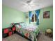 A cozy bedroom features a window, a ceiling fan, and bright green walls with colorful dinosaur themed bedding at 8815 W Quarto Cir, Littleton, CO 80128