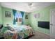 A cozy bedroom features a window, a ceiling fan, and bright green walls with colorful dinosaur themed bedding at 8815 W Quarto Cir, Littleton, CO 80128