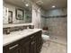Bathroom featuring a marble vanity, decorative mirror, and tiled shower at 4483 W Cottonwood Pl, Littleton, CO 80123