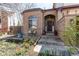 Charming brick home featuring a garden, bench, and an arched entryway with a dark-colored door at 9754 Las Colinas Dr, Lone Tree, CO 80124