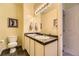 Bathroom featuring a double sink vanity, large mirror with lighting, and a white toilet at 9519 Pearl Cir # 105, Parker, CO 80134