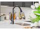 This kitchen displays a gooseneck faucet over a stainless sink, complemented by quartz countertops and white backsplash at 1900 E Girard Pl # 505, Englewood, CO 80113