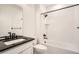 Bathroom featuring a combined shower and tub with white subway tile and dark fixtures and countertop at 2484 W 69Th Pl, Denver, CO 80221