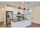 Modern kitchen boasts an island, stainless steel appliances, crisp white cabinetry, and stylish pendant lights at 2484 W 69Th Pl, Denver, CO 80221