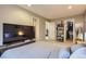 Bright bedroom boasts gray-striped bedding, a television, and open closet for organization at 4063 S Quintero Way, Aurora, CO 80013