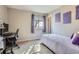 Comfortable bedroom boasts purple wall decor, a desk, and natural light from the window at 4063 S Quintero Way, Aurora, CO 80013