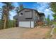 Exterior view of gray two-story home with a garage, trees, and a well-maintained lawn at 30273 Conifer Rd, Evergreen, CO 80439