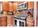Close-up of a kitchen with stainless steel appliances, wood cabinetry, and detailed backsplash at 30273 Conifer Rd, Evergreen, CO 80439