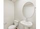 Small half bath features pedestal sink, oval mirror, and toilet at 6531 N Malaya St, Aurora, CO 80019