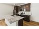 Modern kitchen features dark wood cabinets, stainless steel appliances, granite counters and wood-look flooring at 6531 N Malaya St, Aurora, CO 80019