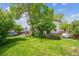 Large grassy backyard with mature trees and a partially-covered back patio at 8552 Gray Ct, Arvada, CO 80003