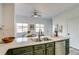 Bright kitchen features green cabinetry and an island with a stainless steel sink at 2642 Devonshire Ct, Denver, CO 80229