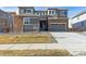 Two-story home with gray siding, stone accents, and a two-car garage at 1749 Marlowe E Cir, Erie, CO 80516