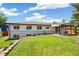 Wide backyard view with lush lawn, garden beds, covered patio, and a light neutral home exterior at 1354 S Wright St, Lakewood, CO 80228