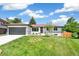 Single-story home featuring green grass, landscaping, mature trees, a gray garage door, and a tidy lawn at 1354 S Wright St, Lakewood, CO 80228