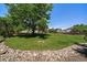 Expansive backyard featuring lush green grass, mature trees, and a charming rock border at 11506 Greenbriar Ln, Parker, CO 80138