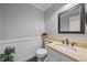Stylish powder room with a marble countertop, framed mirror, and white wainscoting at 11506 Greenbriar Ln, Parker, CO 80138