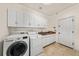 Well-organized laundry room with ample cabinet space, modern washer and dryer, utility sink, and tiled floor for easy maintenance at 2019 Clipper Dr, Lafayette, CO 80026