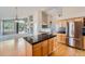 Bright kitchen with a black granite island, stainless steel refrigerator, and hardwood floors at 22436 E Maplewood Pl, Aurora, CO 80015