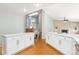Open-concept kitchen with island seating, white cabinetry, modern appliances, and hardwood floors leading to stairs at 742 Megan Ct, Longmont, CO 80504