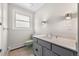 Bathroom featuring gray cabinets, neutral countertop, a window and classic wall sconces at 1487 W Fair Ave, Littleton, CO 80120