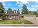 Charming two-story home featuring a brick facade, well-manicured lawn, mature trees, and an attached two car garage at 1487 W Fair Ave, Littleton, CO 80120