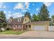 Charming two-story home boasts a brick facade, yellow siding, dormer windows, and an attached two-car garage at 1487 W Fair Ave, Littleton, CO 80120