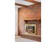 Close up of a brick fireplace with a wooden mantle and a glass-enclosed firebox at 1487 W Fair Ave, Littleton, CO 80120