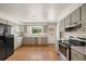 Well-lit kitchen with gray cabinets, stainless steel appliances, and a window overlooking the backyard at 1487 W Fair Ave, Littleton, CO 80120
