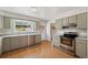 Well-lit kitchen featuring wood floors, modern appliances, light cabinets, and a window overlooking the backyard at 1487 W Fair Ave, Littleton, CO 80120