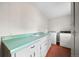 Bright laundry room with a green countertop, white cabinets, and a washing machine at 1487 W Fair Ave, Littleton, CO 80120