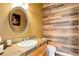 Powder room with wood-look wall and oval mirror at 19701 Hunting Downs Way, Monument, CO 80132