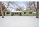 Green Ranch home with snowy front yard and landscaping at 1876 S Chester Cir, Denver, CO 80247