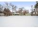 Green Ranch home with detached garage, snowy yard, and trees at 1876 S Chester Cir, Denver, CO 80247