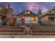 Inviting home featuring a stone accent wall, fenced yard, and blooming tree, all beautifully illuminated at dusk at 2767 W 38Th Ave, Denver, CO 80211