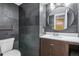 Modern bathroom featuring sleek slate tile, updated vanity, and stylish round mirror at 19844 E Vassar Ave, Aurora, CO 80013