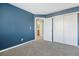 A bedroom with blue walls, carpet, closet, and doorway to another room at 19844 E Vassar Ave, Aurora, CO 80013