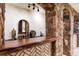 Custom wet bar featuring stone accents, wood countertop, sink, decorative bar, and under-cabinet lighting at 7188 Raphael Ln, Littleton, CO 80125