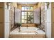 Spa-like bathroom features a soaking tub, stone wall, and wood window shutters at 7188 Raphael Ln, Littleton, CO 80125