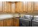 Functional laundry room with wood cabinets, granite counters, a sink, and modern Samsung washer and dryer at 7188 Raphael Ln, Littleton, CO 80125
