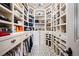 Luxurious walk-in closet featuring custom shelving, drawers, and elegant chandelier at 7188 Raphael Ln, Littleton, CO 80125