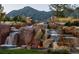 Beautiful, illuminated, multi-tiered rock waterfall feature with natural stone elements and vibrant greenery at 7188 Raphael Ln, Littleton, CO 80125