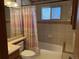 Full bathroom with tiled walls, tub and shower with window at 11375 W Maplewood Ave, Littleton, CO 80127