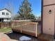 View of the deck with a wood railing, snow on the rock ground, and the neighbor's house in the background at 11375 W Maplewood Ave, Littleton, CO 80127