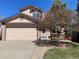 Tan two-story home showcasing an attached two-car garage and covered front porch seating area at 11375 W Maplewood Ave, Littleton, CO 80127