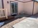 Cozy backyard patio area with sliding glass door and table, with a walkway made of paving stones and decorative rock at 11375 W Maplewood Ave, Littleton, CO 80127